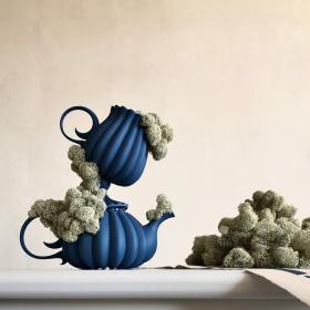 Färgfoto. Två blå keramikkannor på varandra, delvis täckta av renlav.