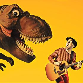 visar artisten Kapten Kapsyl, en man med gitarr och en dinosaurie